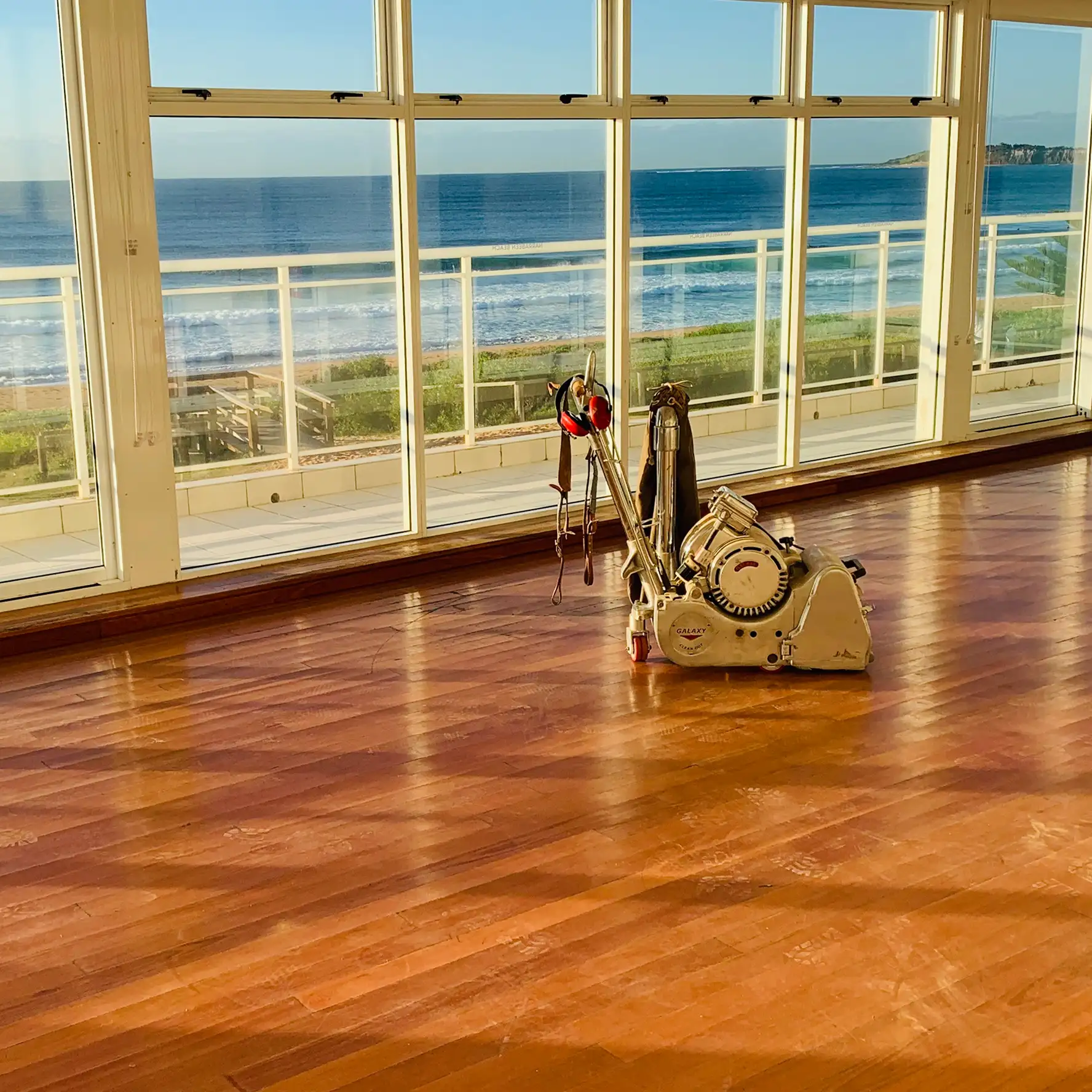 Reddish-brown Merbau timber floor with high-gloss finish in a coastal Sydney home overlooking the beach